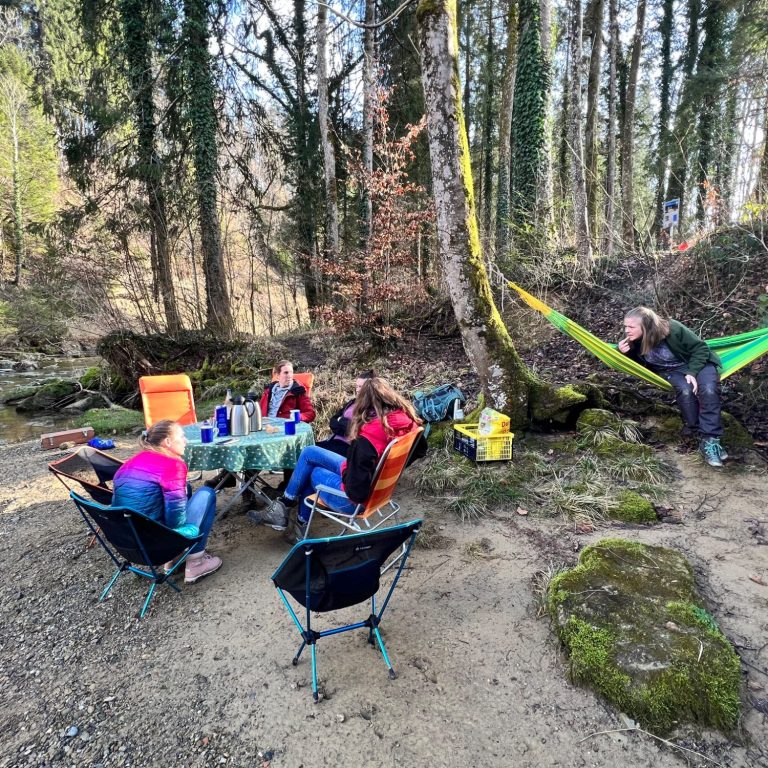 Gemeinsame Naturerlebnisse verbinden Eine Gruppe verbringt gemeinsam Zeit an einem Lagerplatz im Wald.
